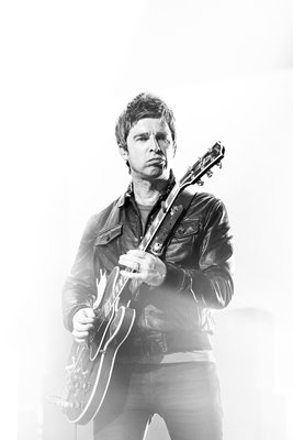 Noel Gallagher plays guitar on stage