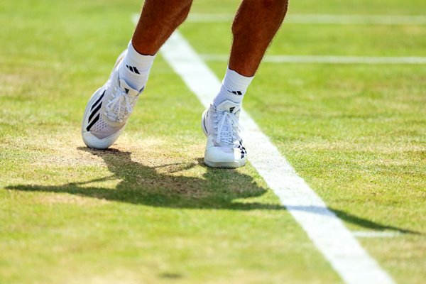 General view player serving feet behind baseline Grass Court 2024