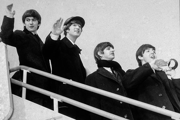 The Beatles wave from airplane steps