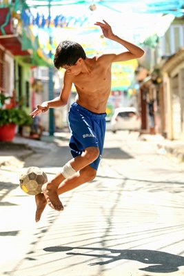 A young boy plays football on the streets of Manaus