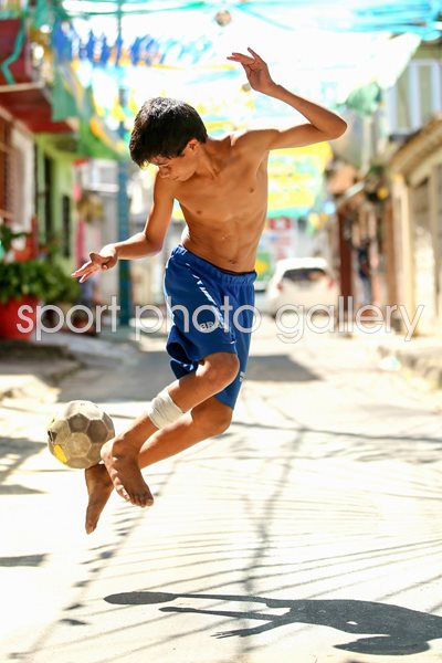 A young boy plays football on the streets of Manaus 